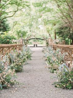 an outdoor wedding ceremony with wooden benches and flowers on the aisle, surrounded by greenery