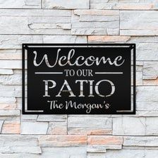 a sign that says welcome to our patio the morgan's on a stone wall