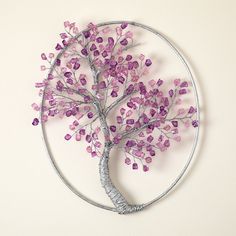 a metal tree with purple beads on it's branches is mounted to the wall