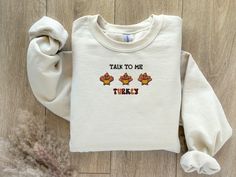 Talk to me turkey is a Funny Thanksgiving embroidered sweatshirt. Wear this warm, cozy, soft, and trendy product on any occasion. Make a statement with this cute turkey embroidery unique design. Also, this design will make a perfect Thanksgiving, fall, birthday, Halloween, and fall festival gift.  Material: * 50% cotton, 50% polyester * Pre-shrunk * Classic fit * 1x1 athletic rib knit collar with spandex * Air-jet spun yarn with a soft feel and reduced pilling * Double-needle stitched collar, sh Fall Fleece Tops With Letter Embroidery, Fleece Sweatshirt With Letter Embroidery For Fall, Fall Fleece Sweater With Embroidered Text, Fleece Sweater With Letter Embroidery For Fall, Fall Embroidered Text Fleece Sweater, Fall Fleece Sweatshirt With Embroidered Text, Fall Fleece Top With Embroidered Graphics, Embroidered Fleece Sweatshirt For Fall, Turkey Embroidery