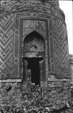 black and white photograph of an old brick building with a door in the middle surrounded by rocks