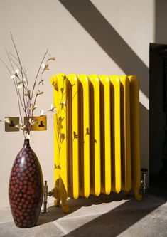 a yellow radiator next to a vase with flowers