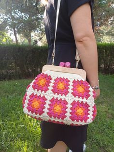 a woman holding a crocheted purse in her hands