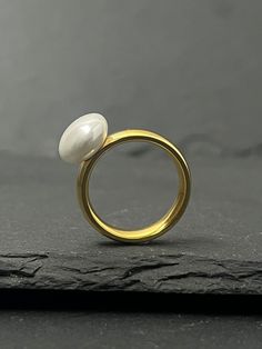 Modern ring with a cultured pearl. Trendy minimalist jewelry with a geometric design. Timeless and classic style, this ring will make a beautiful gift without lacking in taste. 3 sizes are available: 52 EU / 6 US inner diameter of 16.5 mm. 54.4 EU / 7 US inner diameter of 17.3 mm. 57 EU / 8 US inner diameter of 18.1 mm. Cultured pearl: button shape 18K gold color Weight: 4.9 grams Frame on stainless steel. Stainless steel is non-corrosive. It does not oxidize like silver, it will resist over tim Modern Pearl Wedding Ring, Modern Pearl Ring For Formal Occasions, Modern Pearl Rings For Anniversary, Modern Gold Pearl Ring, Modern Pearl Open Ring For Anniversary, Modern Gold Pearl Ring For Wedding, Modern Open Pearl Ring For Anniversary, Modern Everyday Pearl Ring, Modern Gold Pearl Ring For Everyday