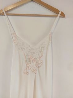 Beautiful vintage slip dress (circa 1980s) in ivory, with pretty lace and pink embroidery detail. Full length, with criss-cross straps at back, lace trim and split to left leg. Glamorous nightwear, vintage evening slip dress, or dress down and wear over a t-shirt and with trainers. Material: Label is washed out - suspect polyester. Condition: Great vintage condition - no obvious marks or damage Recommended care: Machine washable Sizing: Label is washed out - please see exact measurements below; Ivory Slip Dress, Slip Dress Vintage, Vintage Slip Dress, Vintage Slip, Pink Embroidery, Vintage Slips, Women's Nightgowns, Nightgowns, Embroidery Details