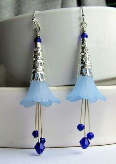 Add a touch of whimsy to any outfit with our Lucite Flower Earrings! These frosted flowers come in a beautiful blue or purple, paired with bright silver cones and sparkling crystals. Perfect for adding a pop of color and fun to your look. Lead & Nickel Free Silver Plating Measures 3 1/4 inches (approximately) in length from the very top of the ear wire Available in Blue and Purple (the purple is a richer tone than the photo depicts) Frosted Lucite Flower, Decorative Bright Silver Cones, and Faceted Purple crystals. Made in the U.S.A. Whimsical Blue Dangle Flower Earrings, Blue Whimsical Dangle Flower Earrings, Whimsical Blue Jewelry With Flower Charm, Whimsical Blue Flower Earrings, Whimsical Blue Earrings For Party, Blue Flower Earrings With Ear Wire For Party, Nickel-free Blue Flower Earrings For Wedding, Blue Sterling Silver Flower Earrings, Whimsical Blue Jewelry For Parties