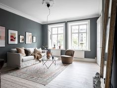 a living room filled with furniture and paintings on the wall next to a large window