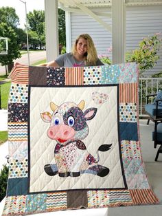 a woman holding up a quilt with a cow on it