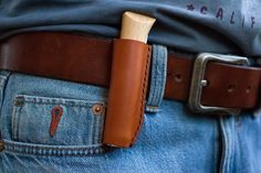 a leather belt with a wooden handle on it and jeans in the back pocket,