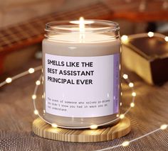 a candle that says smells like the best assistant ever on it sitting next to a guitar