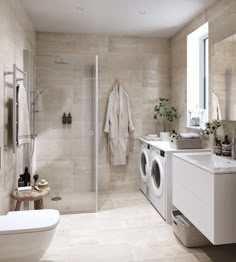 a washer and dryer in a bathroom with beige tile walls, flooring and white fixtures