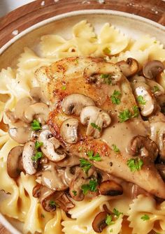 a plate of pasta with chicken, mushrooms and parsley