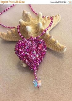 a pink beaded heart hanging from a necklace on a brown table with a starfish charm