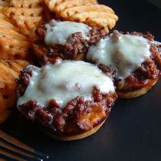 three sloppy joes on a plate with crackers and cheesy toppings