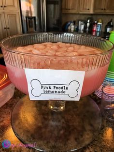 pink poodle lemonade in a glass bowl on a counter top with a sign that says, pink poodle lemonade