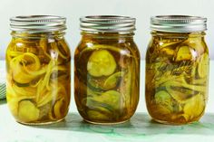 three jars filled with pickles sitting on top of a table