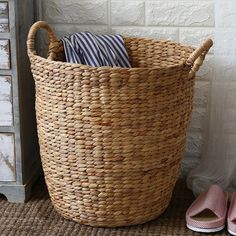 a pair of pink slippers sitting next to a large woven basket on the floor