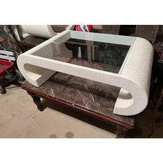 a coffee table with a glass top and marble base on display in a room full of other furniture