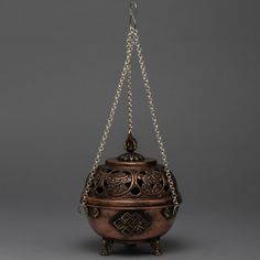 an ornate metal container with chains hanging from it's sides, on a gray background