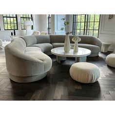 a living room filled with furniture on top of a hard wood floor covered in lots of windows