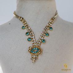 a gold necklace with blue and white stones on top of a mannequin head