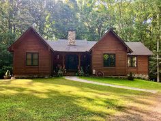 a log cabin sits in the middle of a wooded area with lots of trees and grass