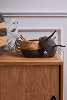 two crocheted baskets sitting on top of a wooden dresser next to a stuffed animal