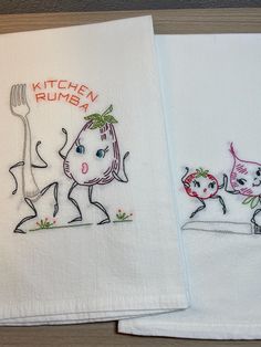 two kitchen towels with embroidered designs on them