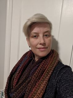 a woman with short hair wearing a multicolored scarf and smiling at the camera