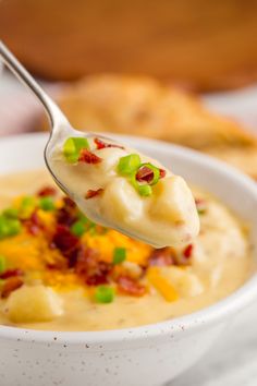 a spoon full of potato soup with bacon and green onions on it's side