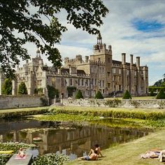 people laying on the grass in front of a castle