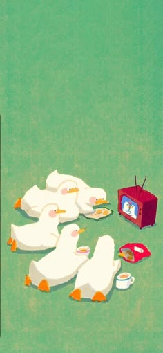 several white ducks sitting on top of a green field next to a red television set