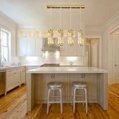 a kitchen with two stools next to an island