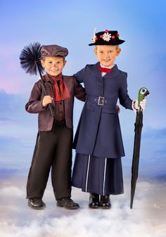 two children dressed in costumes standing next to each other with an umbrella and top hat on