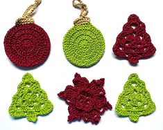 four crocheted ornaments are hanging from chains on a white surface, one is green and the other is red