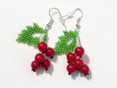 red beads and green leaves are hanging from earrings