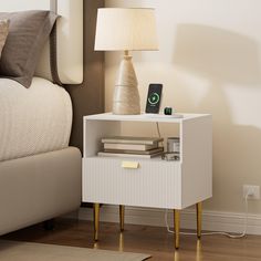 a nightstand with a phone on it next to a night stand and lamp in a bedroom