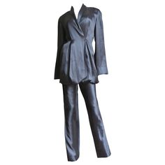 A beautiful black silk pant suit from Yumi Eto. The double breasted shawl collar jacket is gorgeous with matching fine inner adjustable straps which can be moved to different configuration with buttons inside of the jacket to change the hemline shape and length. The pants have straight legs and a back zipper. The jacket has grey mother of pearl buttons in front, all inside seams are beautifully bound finished and both pieces are unlined. Fits sizes Small, Medium. Marked US size 8. Jacket Bust 34 Satin Suits With Long Sleeves For Evening, Long Sleeve Satin Suits For Evening, Satin Long Sleeve Suits For Evening, Evening Satin Suits With Long Sleeves, Chic Silk Party Suits, Elegant Silk Pantsuit For Workwear, Elegant Evening Silk Suits, Elegant Satin Pantsuit For Evening, Luxury Evening Pantsuit With Notch Lapel