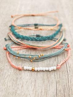 four different bracelets with beads and bead on them sitting on top of a wooden table