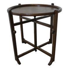 a round wooden table with wheels on the bottom and one leg up against it's side