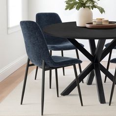 a black table with four blue chairs around it and a potted plant on top