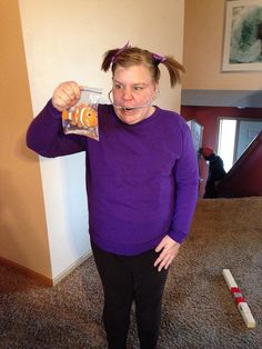 a woman in purple shirt holding up a bag of candy with an orange fish on it