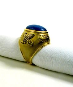 a close up of a napkin with a gold ring on it and a blue stone in the middle