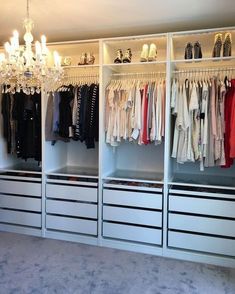 an organized closet with chandelier and clothes hanging on the shelves in front of it