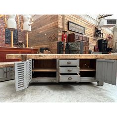 a kitchen island made out of metal and wood with drawers on each side, in front of a brick wall