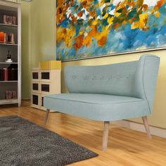 a blue couch sitting in front of a painting on a wall next to a wooden floor