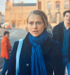 a woman wearing a blue scarf standing in the street