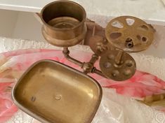 an old fashioned metal device sitting on top of a pink and white table cloth next to a cup