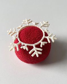 a red ball with white snowflakes on it sitting on top of a table