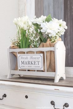 a basket with flowers in it sitting on top of a dresser